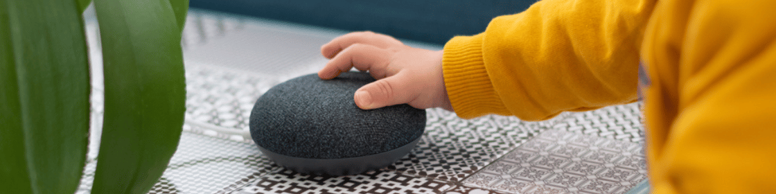 A small child's hand on a home smart speaker